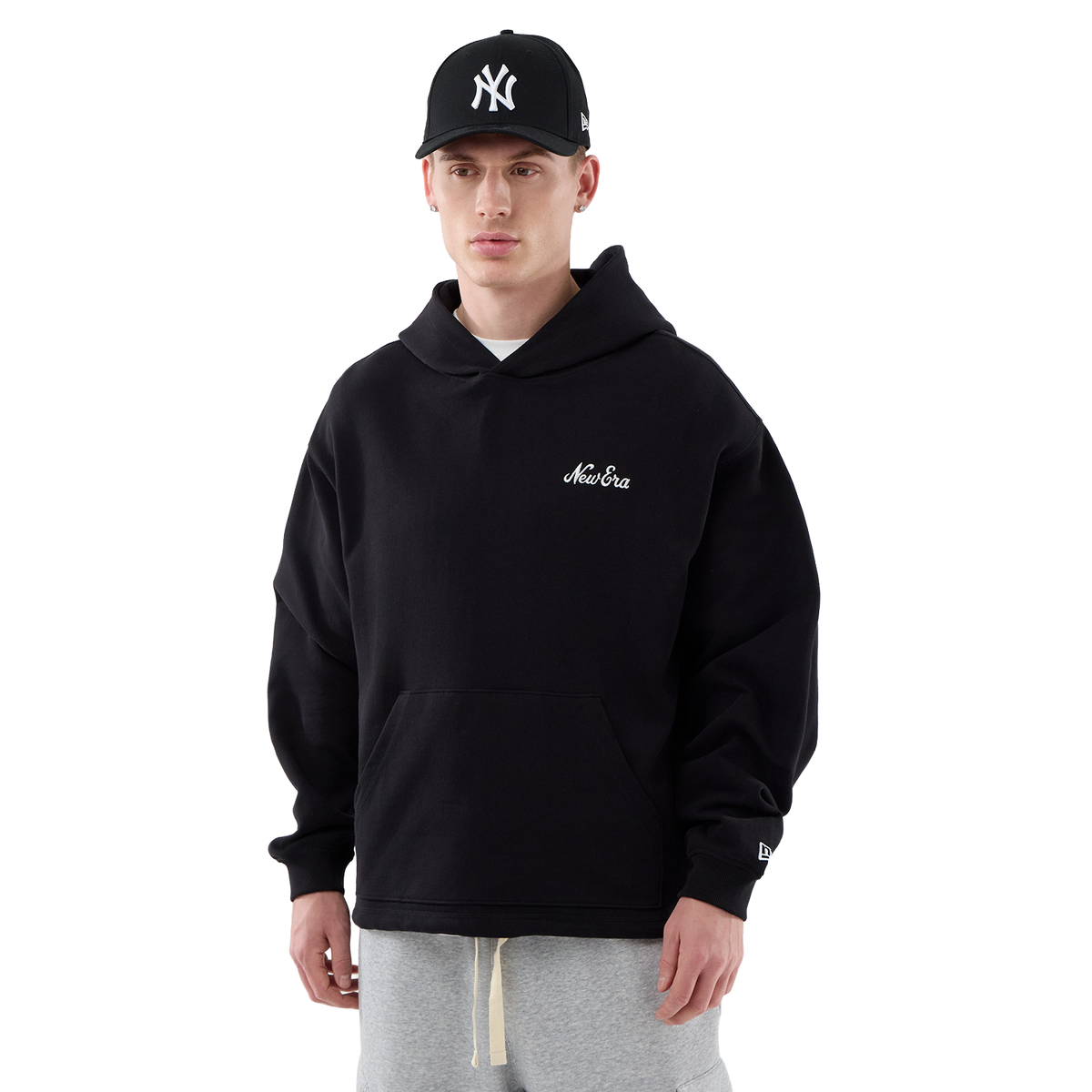 New Era Hoodie in Schwarz, Model von vorne in voller Figur mit Cap