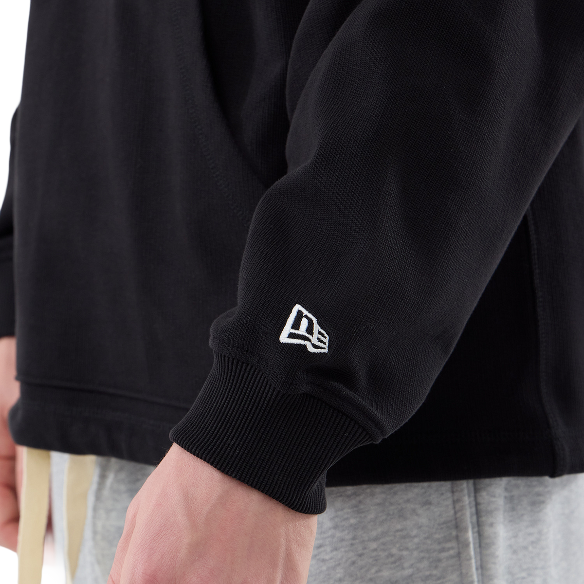 New Era Hoodie in Schwarz, Detail des Ärmelbündchens mit Flaggen-Logo